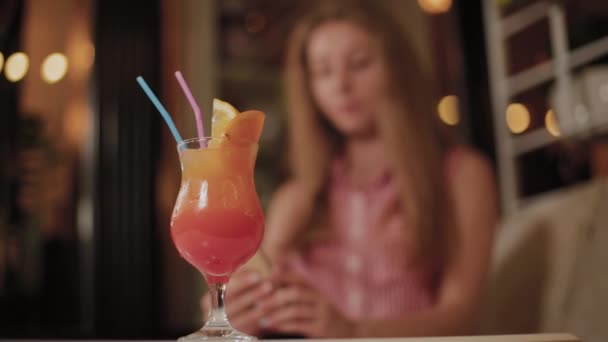 Beautiful girl with a beautiful fresh bright bright evening cocktail in a cafe. — Stock Video