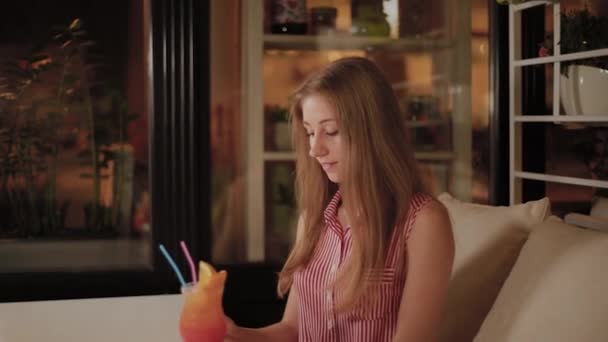 Belle fille avec un beau cocktail du soir lumineux et frais dans un café . — Video