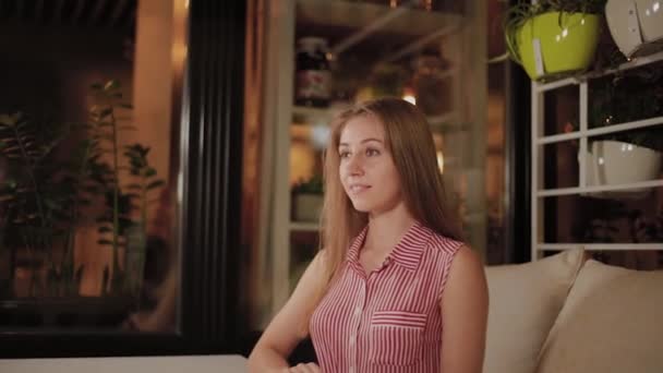 Belle fille en attente de sa commande dans un café du soir . — Video