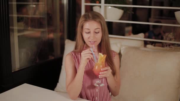 Menina bonita com um belo cocktail de noite brilhante fresco brilhante em um café . — Vídeo de Stock