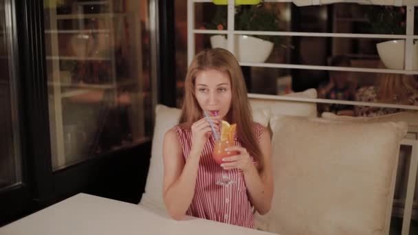 Menina bonita com um belo cocktail de noite brilhante fresco brilhante em um café . — Vídeo de Stock