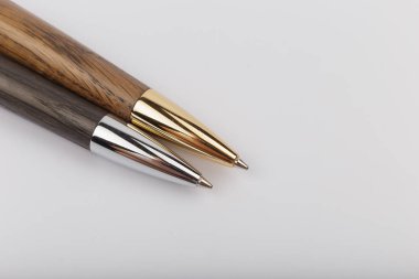 Beyaz arka plan üzerinde ahşap ve metalden yapılmış iki el yapımı tükenmez kalem.