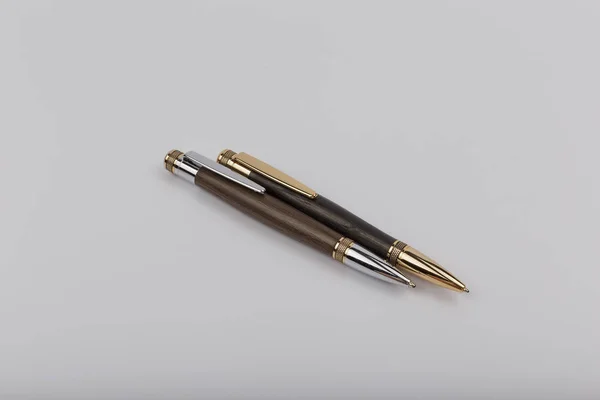 Two handmade ballpoint pens made of wood and metal on a white background.