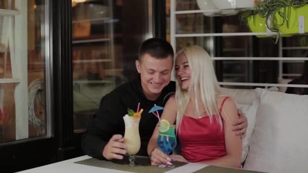 Krásná dívka a chlápek s čerstvými koktejly v večerní kavárně. — Stock video