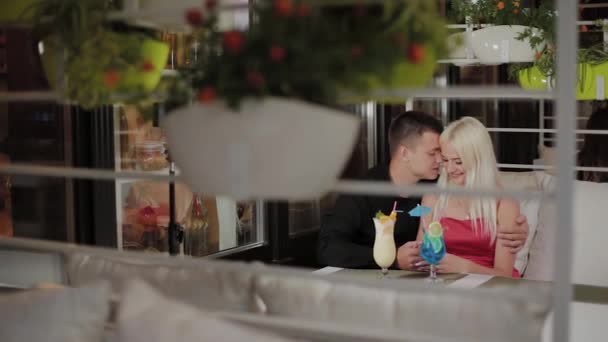 Mooi meisje en kerel met verse cocktails in het avond café. — Stockvideo