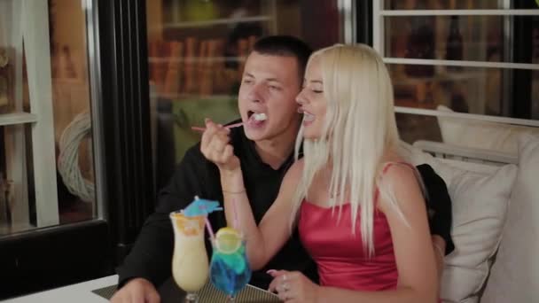 Krásná dívka a chlápek s čerstvými koktejly v večerní kavárně. — Stock video