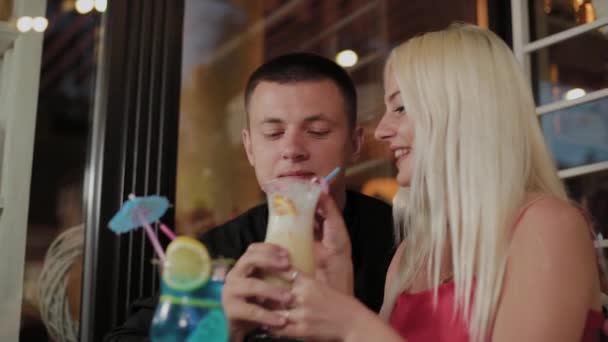 Piękna dziewczyna i facet ze świeżych koktajli w wieczornej kawiarni. — Wideo stockowe