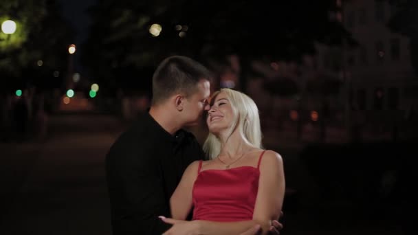 Amantes felizes abraçando em um beco da cidade à noite à luz das lanternas . — Vídeo de Stock