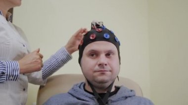 Doktor bir adama insan beyninin çalışması için bir kulaklık takıyor..