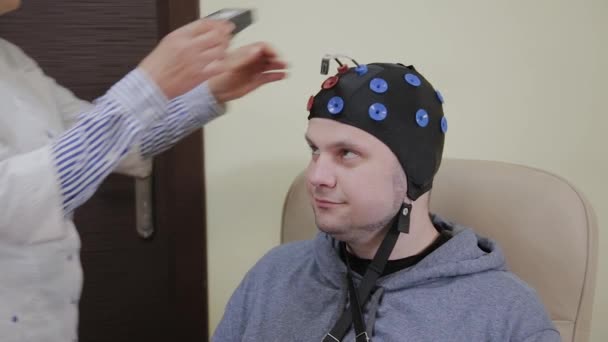 Le médecin met sur un homme un casque pour l'étude du cerveau humain . — Video