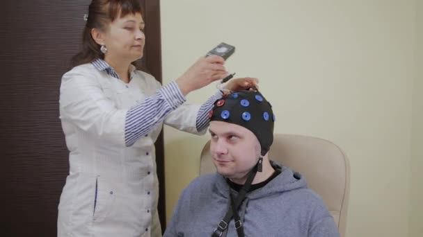 Ο γιατρός βάζει έναν άντρα με ακουστικά για τη μελέτη του ανθρώπινου εγκεφάλου.. — Αρχείο Βίντεο
