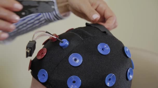 Il medico mette su un uomo un auricolare per lo studio del cervello umano . — Video Stock