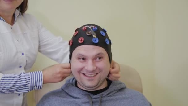 Le médecin met sur un homme un casque pour l'étude du cerveau humain . — Video