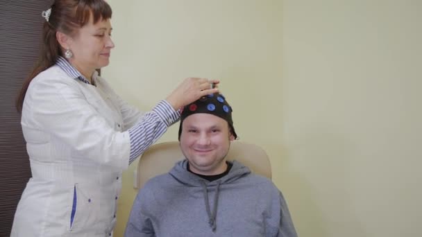 De arts legt een man een headset voor de studie van het menselijk brein. — Stockvideo