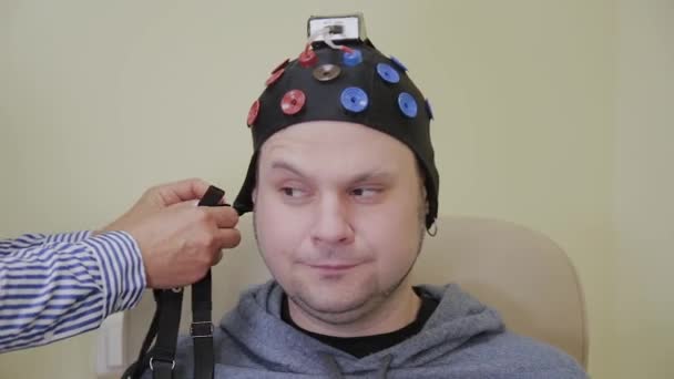 Doktor klade na člověka sluchátka s mikrofonem pro studium lidského mozku.. — Stock video