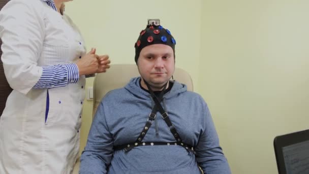 Le médecin met sur un homme un casque pour l'étude du cerveau humain . — Video