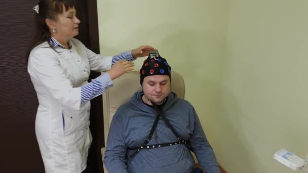 Le médecin met sur un homme un casque pour l'étude du cerveau humain . — Video