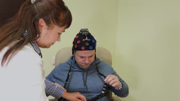 El médico le pone a un hombre un auricular para el estudio del cerebro humano . — Vídeo de stock