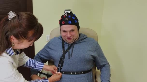 De arts legt een man een headset voor de studie van het menselijk brein. — Stockvideo