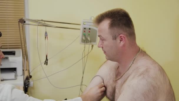 El médico masculino examina a un paciente con un dispositivo médico . — Vídeos de Stock