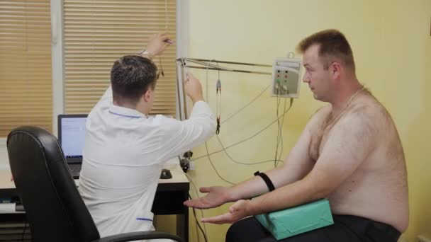 Erkek doktor tıbbi cihaz ile bir hasta muayene. — Stok video