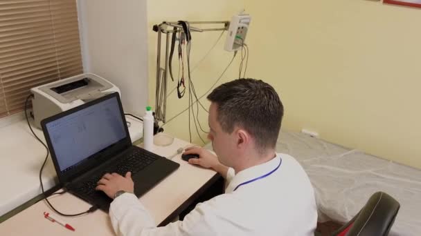 医者の男は診療所のコンピュータで働く. — ストック動画