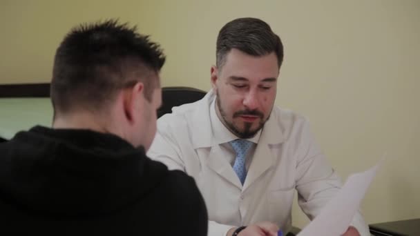 Male doctor takes a patient in his office. — Stock Video