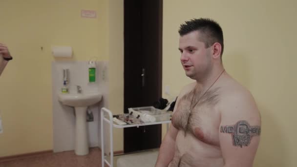 Para un paciente en una clínica, una enfermera masculina coloca un dispositivo en su cuerpo para estudiar los parámetros corporales . — Vídeos de Stock