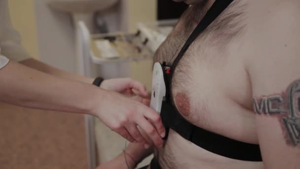 Пациенту в клинике медбрат надевает на его тело устройство для изучения параметров тела. . — стоковое видео