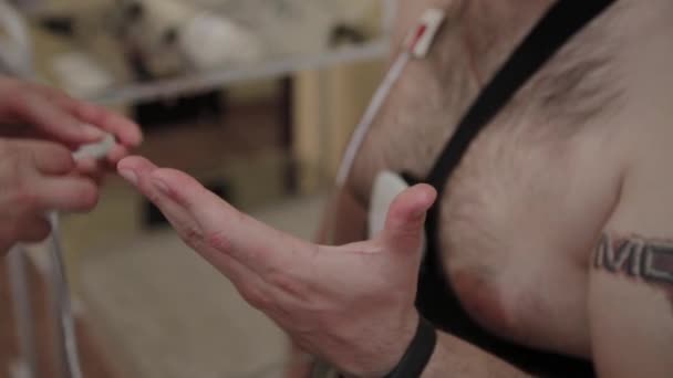 Para um paciente em uma clínica, um enfermeiro coloca um dispositivo em seu corpo para estudar os parâmetros do corpo. . — Vídeo de Stock