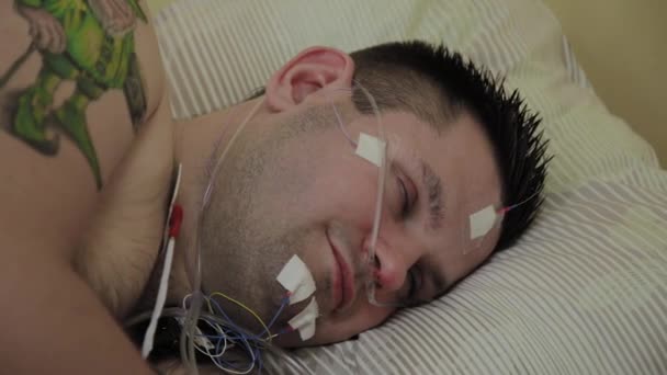 Ο ασθενής είναι ένας άντρας ξαπλωμένος σε έναν καναπέ με μια συσκευή για εξέταση στο σώμα. — Αρχείο Βίντεο