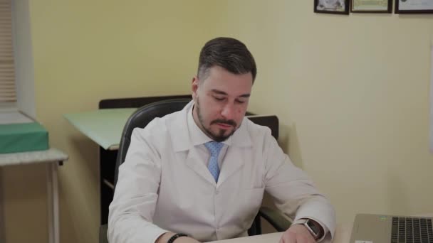 Médico masculino escribe en un cuaderno en la mesa . — Vídeos de Stock