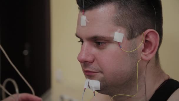 To a patient in a clinic, a male nurse puts a device on his body to study body parameters. — Stock Video