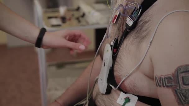 Ahhoz, hogy a beteg egy klinikán, egy férfi nővér tesz egy eszközt a testén, hogy tanulmányozza a test paramétereit. — Stock videók