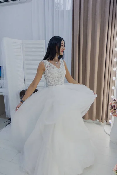 Hermosa chica se prueba un vestido de novia en un salón de novias . —  Fotos de Stock