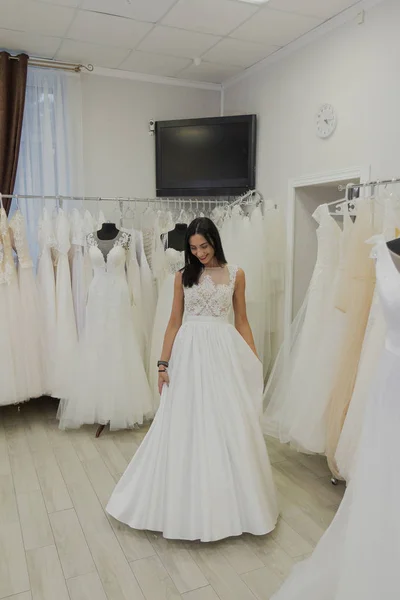 Hermosa chica se prueba un vestido de novia en un salón de novias . —  Fotos de Stock