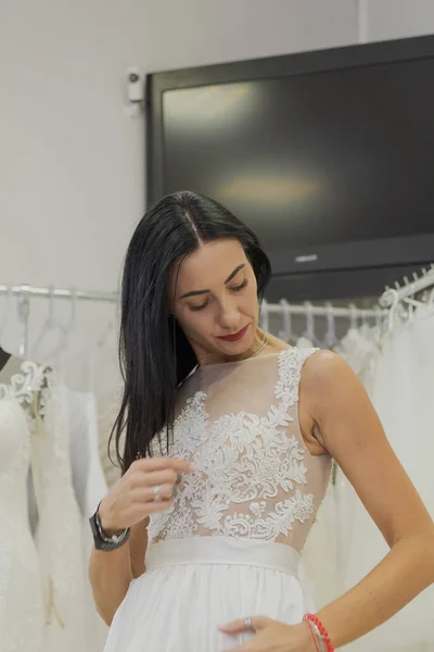 Hermosa chica se prueba un vestido de novia en un salón de novias . — Foto de Stock