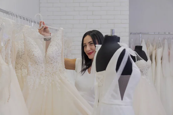 Hermosa chica elige un vestido de novia en un salón de novia . — Foto de Stock