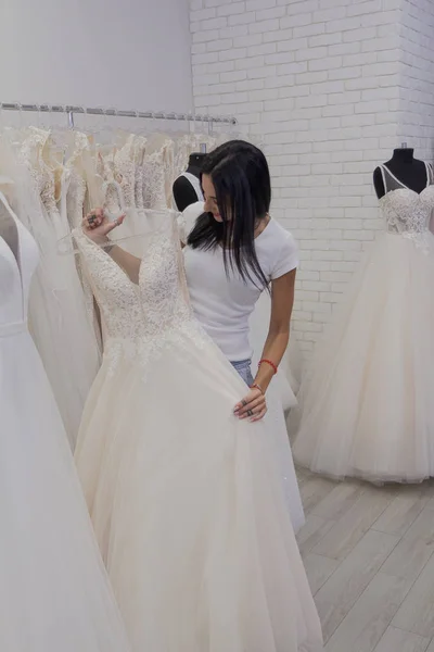 Hermosa chica elige un vestido de novia en un salón de novia . — Foto de Stock