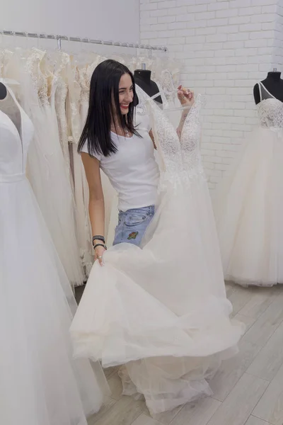 Hermosa chica elige un vestido de novia en un salón de novia . — Foto de Stock