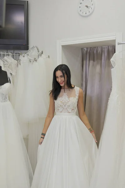 Menina bonita tenta em um vestido de noiva em um salão de noiva . Imagens Royalty-Free