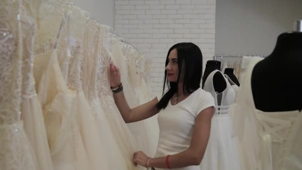 Mooi meisje kiest een trouwjurk in een bruids salon. — Stockvideo