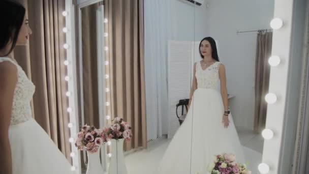 아름다운 소녀는 신부 살롱에서 웨딩 드레스를 측정. — 비디오