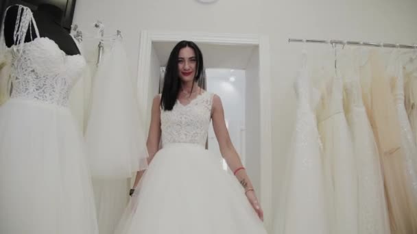 Menina bonita mede um vestido de noiva em um salão de noiva . — Vídeo de Stock