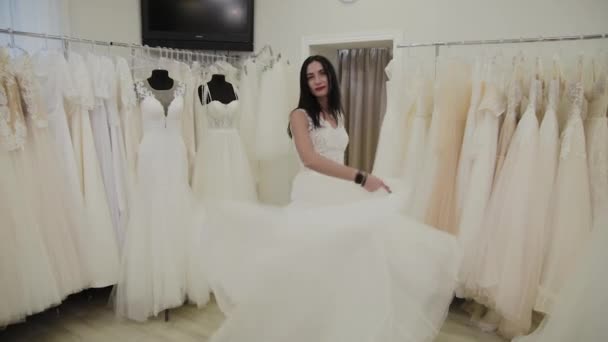 Hermosa chica mide un vestido de novia en un salón de novias . — Vídeos de Stock