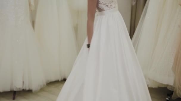 Hermosa chica mide un vestido de novia en un salón de novias . — Vídeos de Stock