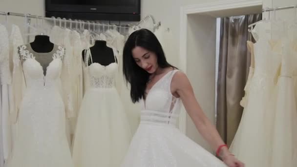 Schöne Mädchen misst ein Hochzeitskleid in einem Brautsalon. — Stockvideo