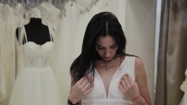 Piękna dziewczyna mierzy suknię ślubną w salonie ślubnej. — Wideo stockowe