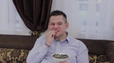 Bir kanepede siyah tohum yiyen yakışıklı adam.