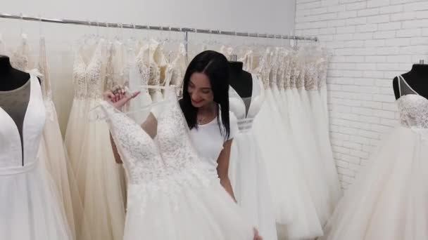Krásná dívka si vybírá svatební šaty v svatebních kadeřnictví. — Stock video